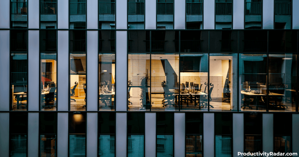 Modern office building at night with illuminated workspaces visible through floor-to-ceiling windows working on
resources