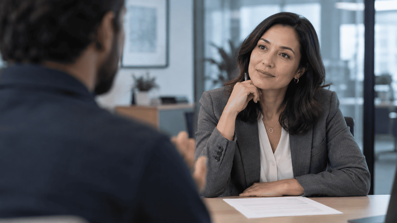 Manager listening across a table as an employee talks, how self-evaluation examples sound to the person reading them